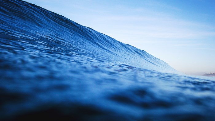 Blue ocean wave under a clear sky