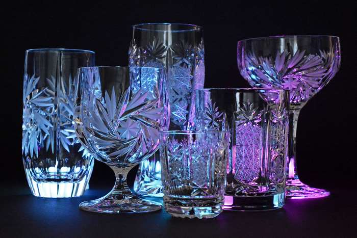 Crystal glasses with intricate patterns illuminated by colored lights