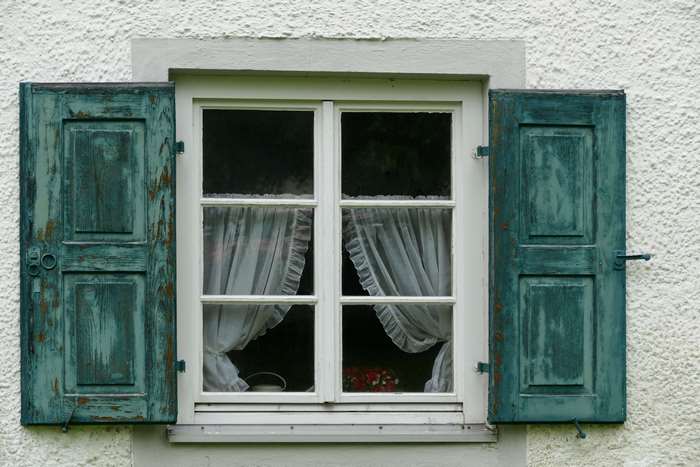Old turquoise blue wooden shutters on a white building window
