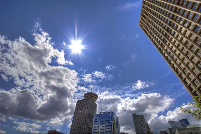 Cityscape with skyscrapers and sun glare under blue sky