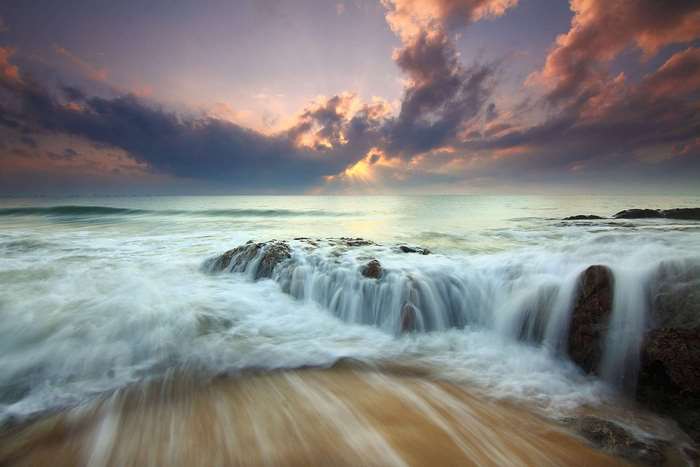 Ocean waves crashing on rocks at sunrise
