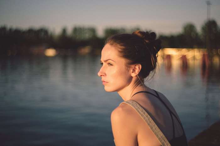 Woman looking out over water at sunset
