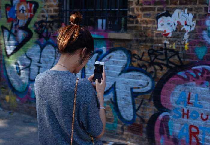 Woman taking a picture of graffiti with her smartphone