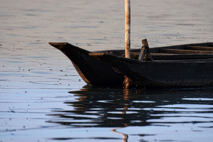 Wooden boat floating on calm water with reflection