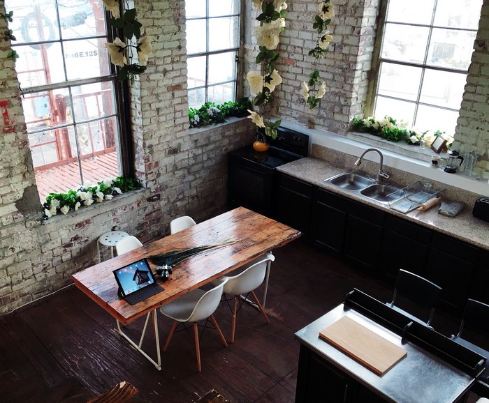 Kitchen with brick walls, wooden table, and laptop
