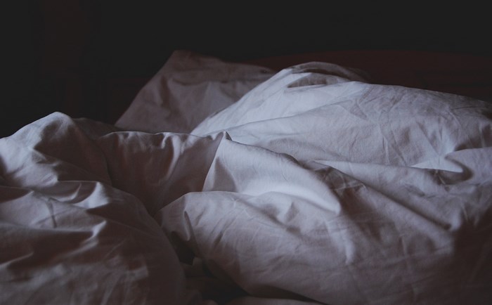 White bedding and sheets in a dark bedroom