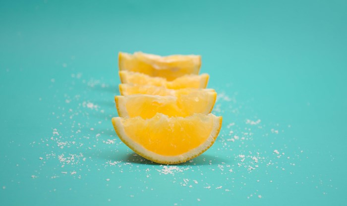 Slices of lemon with salt on a teal background