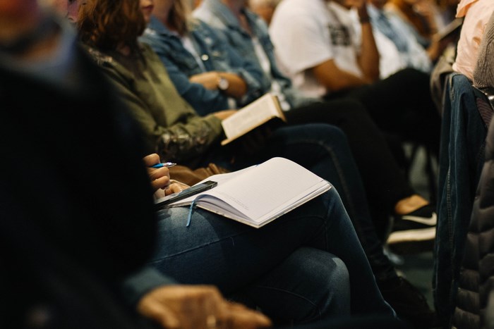People attending a meeting or service with books and notepads