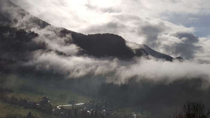 Mountains shrouded in clouds with a village below