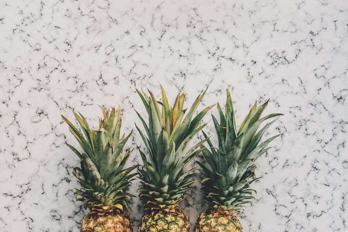 Three pineapples on a marble surface