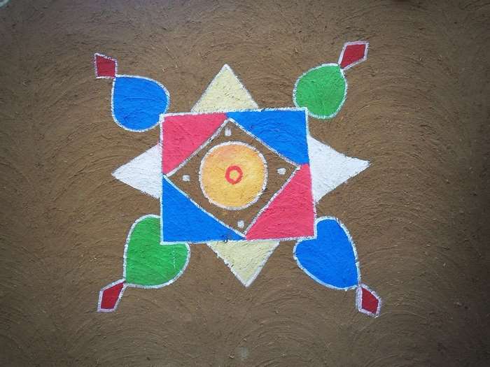 Colorful geometric rangoli design on brown ground