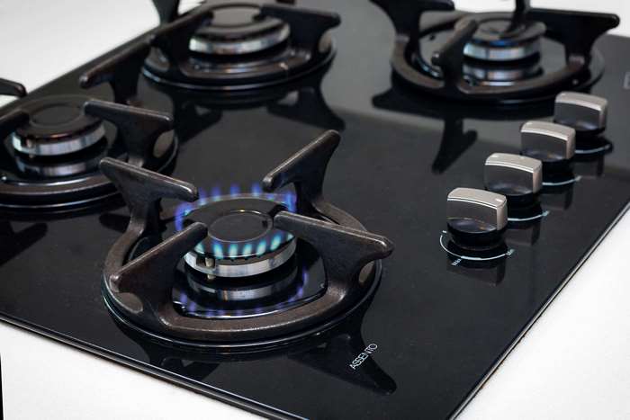 Black glass gas stove with four burners and control knobs