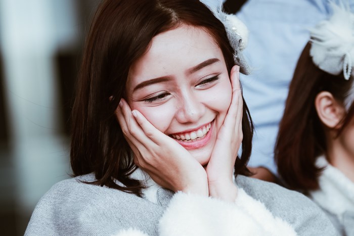 Young woman with hands on cheeks smiling