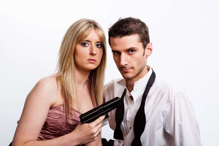 Woman holding gun to man