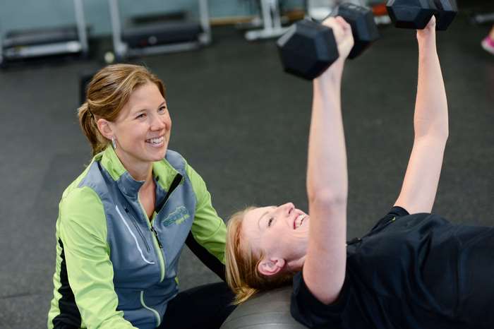 Two women working out with dumbbells in a gym