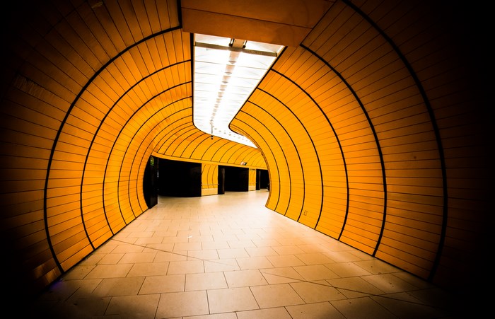 Modern orange tunnel with curved walls and ceiling lights