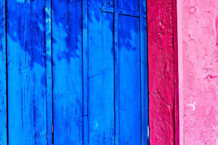 Blue wooden door next to a pink wall