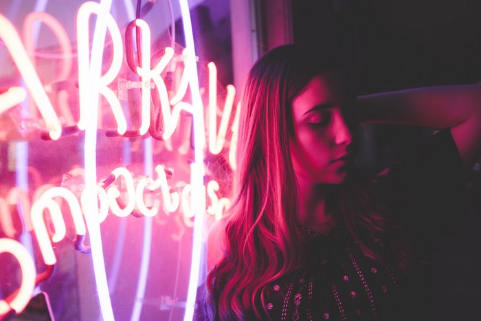 Woman illuminated by pink neon sign