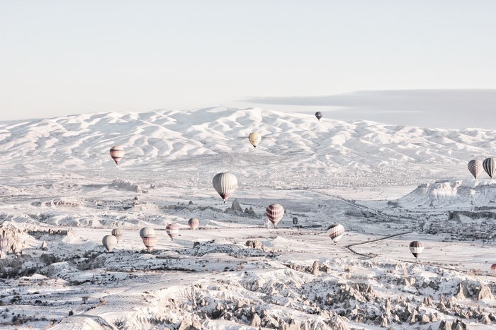 Hot air balloons over a snowy mountain landscape