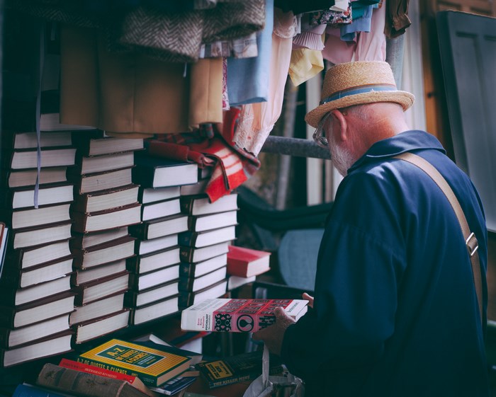 Elderly man in hat browsing books at a market