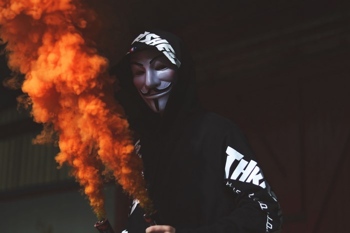 Man in Anonymous mask with orange smoke
