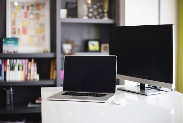Minimalist workspace with MacBook, monitor, and bookshelf