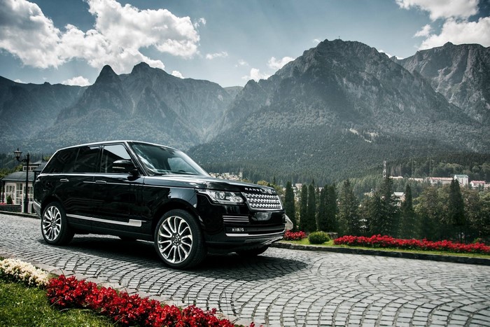 Black Range Rover parked on cobblestone road with mountains
