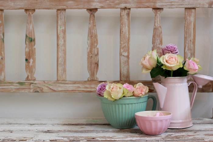 Pastel roses in mint bowl and pink jug on wooden table