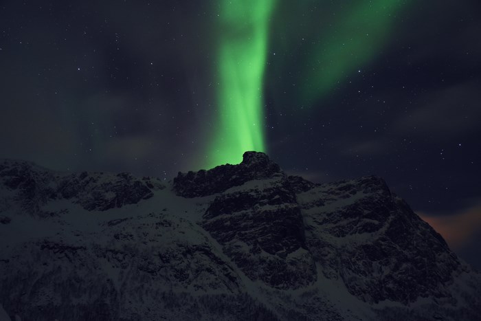 Aurora Borealis over snowy mountains in Tromso