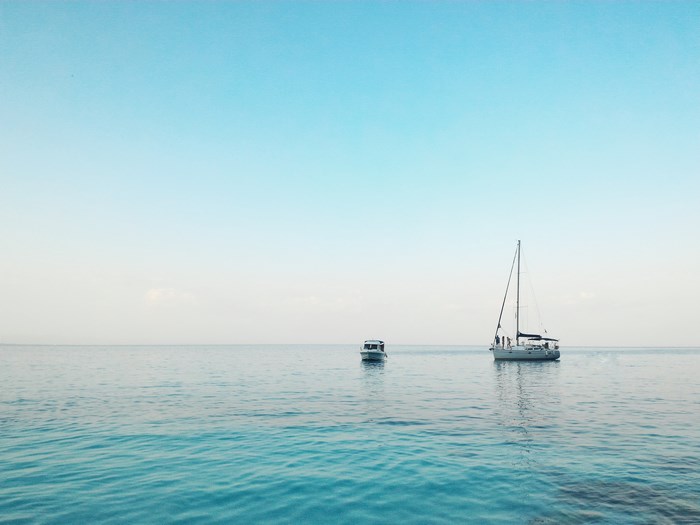 Sailboat and boat on the turquoise ocean under blue sky