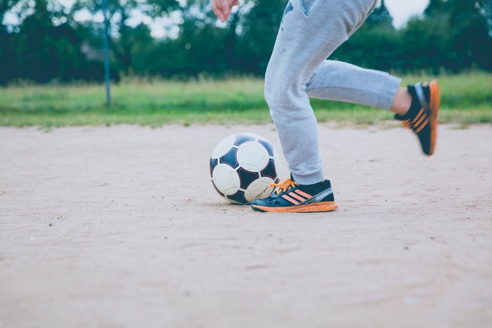 Adidas soccer shoes and ball on sand