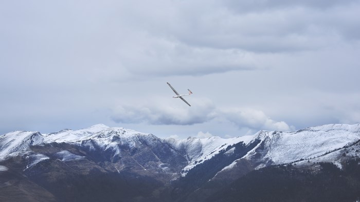 Glider plane flying over snow-capped mountains
