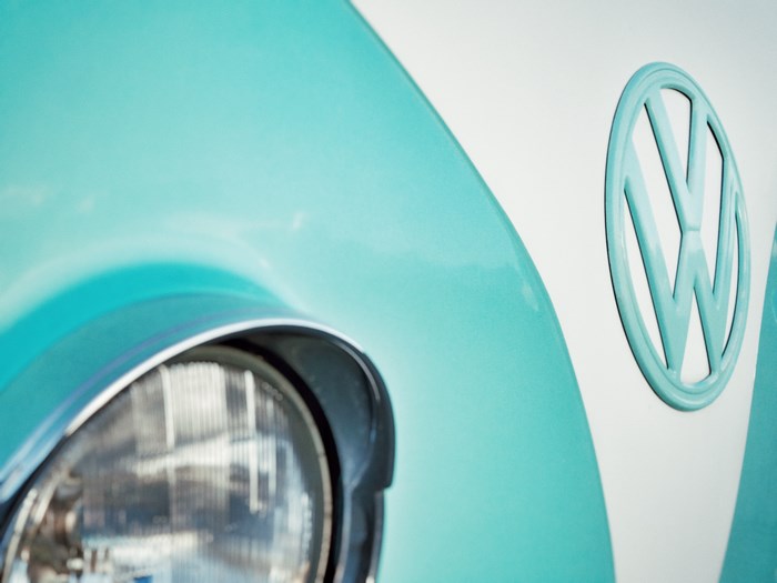 Close-up of a turquoise and white Volkswagen logo and headlight