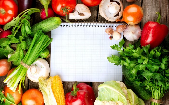 Vegetables and notebook on a wooden table