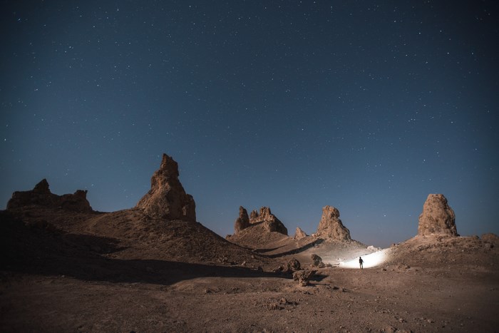 Person with flashlight in Trona Pinnacles desert at night