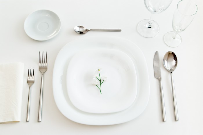 Table setting with plates, cutlery, glasses, and a flower