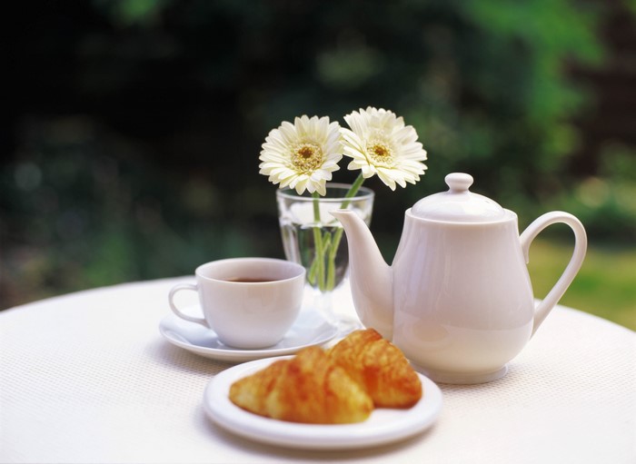 Tea set with croissants and flowers on a table