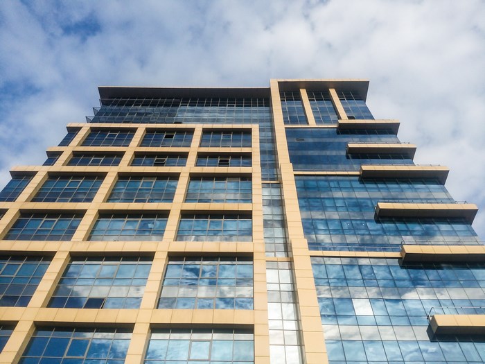 Modern glass and concrete office building against a cloudy sky