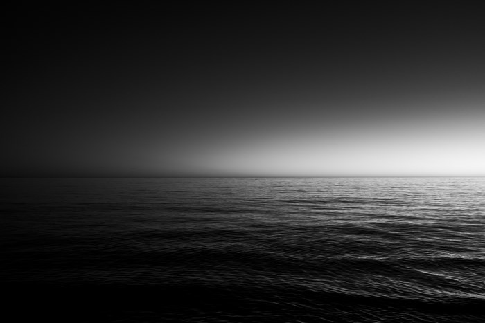 Black and white ocean at dusk with fog
