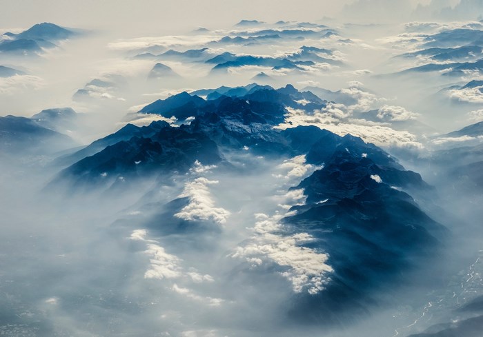 Aerial view of misty blue mountains from above the clouds