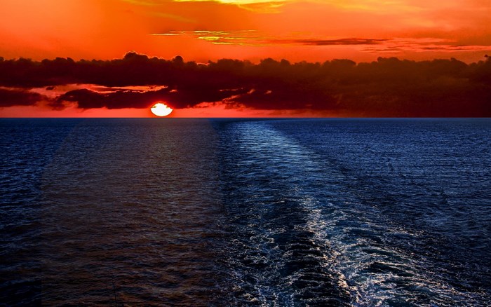 Sunset over the ocean with a wake