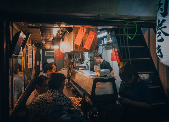 People eating at a Japanese diner counter at night