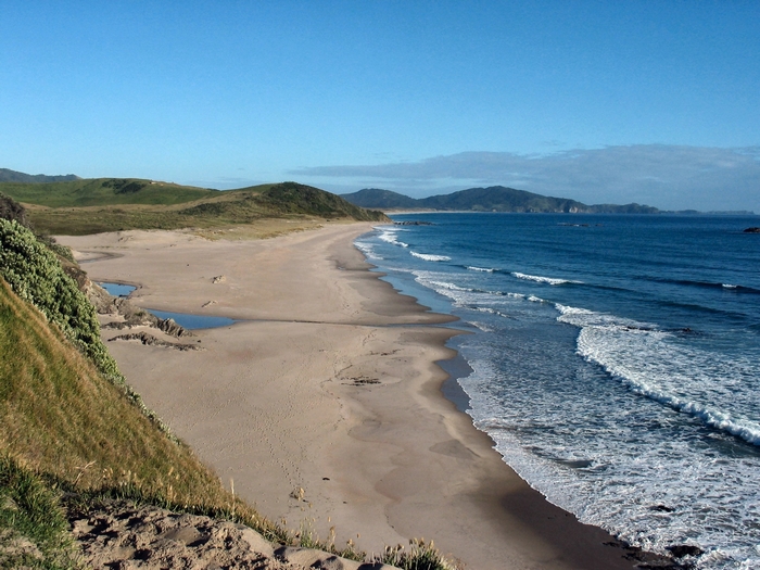 Sandy beach with rolling hills and ocean waves