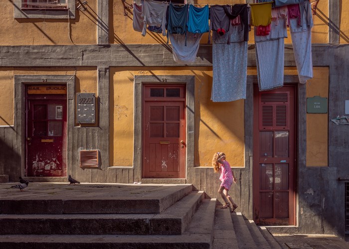 Girl climbing steps in Porto with laundry overhead