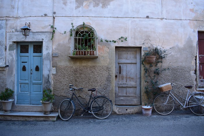 Two bicycles parked outside old buildings with doors and windows