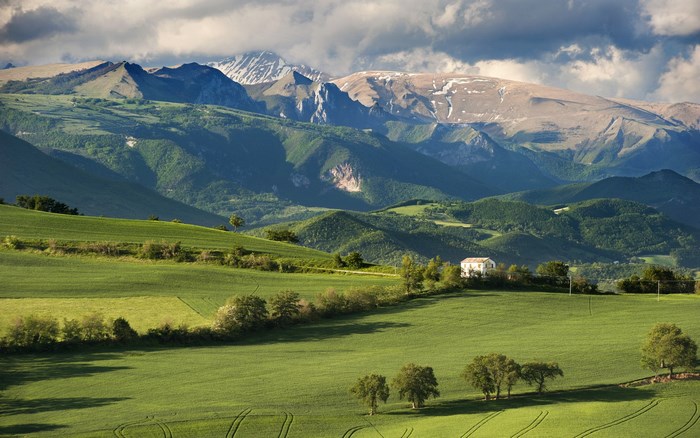 Green rolling hills and mountains under a cloudy sky