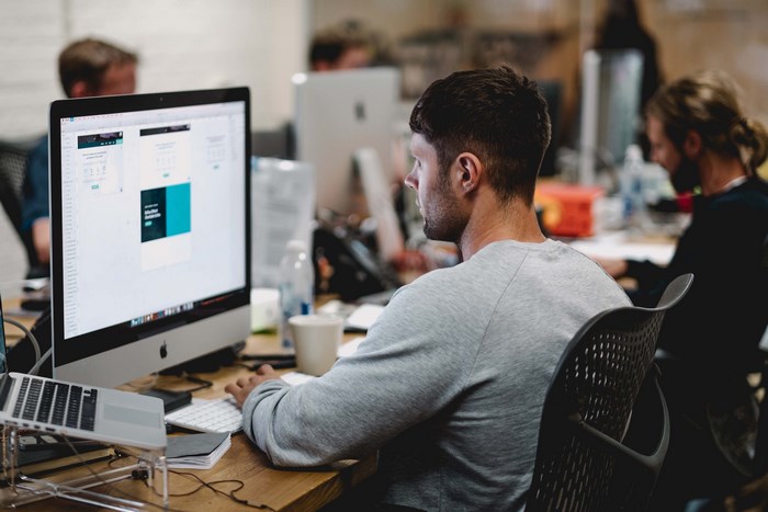 Man working on Apple iMac and MacBook in office