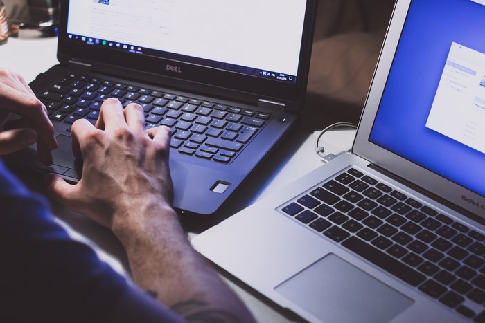 Dell and MacBook laptops with hands typing