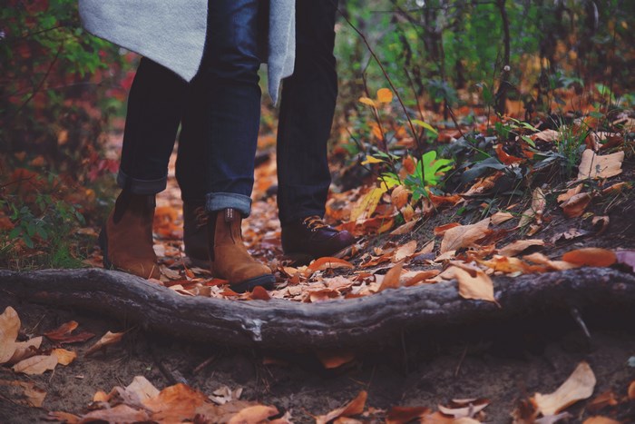 Couple walking on a path covered in autumn leaves