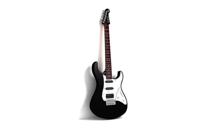Black electric guitar leaning against a white wall